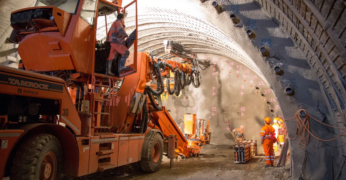 Operarios y jumbo de perforación trabajando sobre el frente de túnel para instalación de micropilotes.
